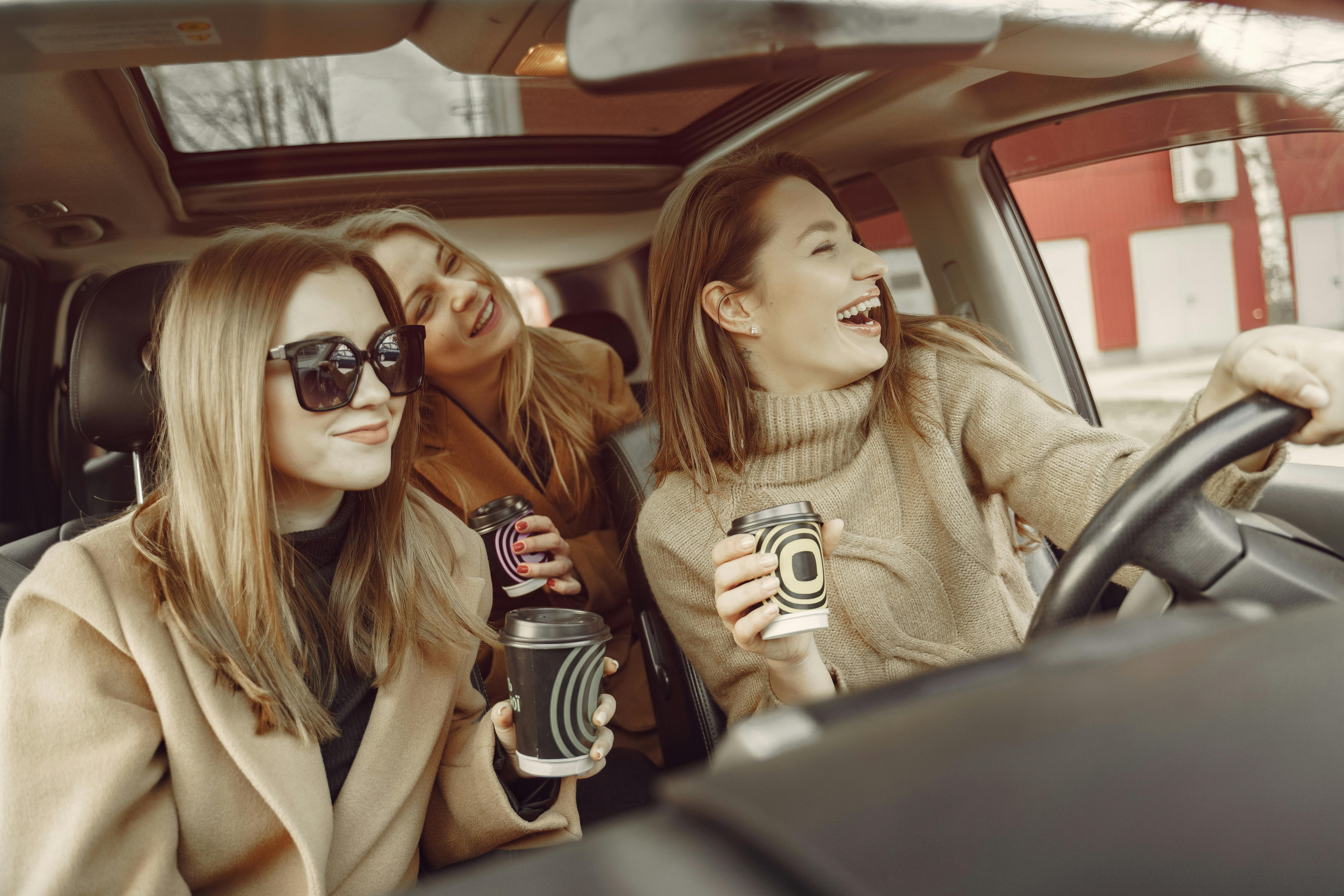 three people in car on road trip, happy and laughing