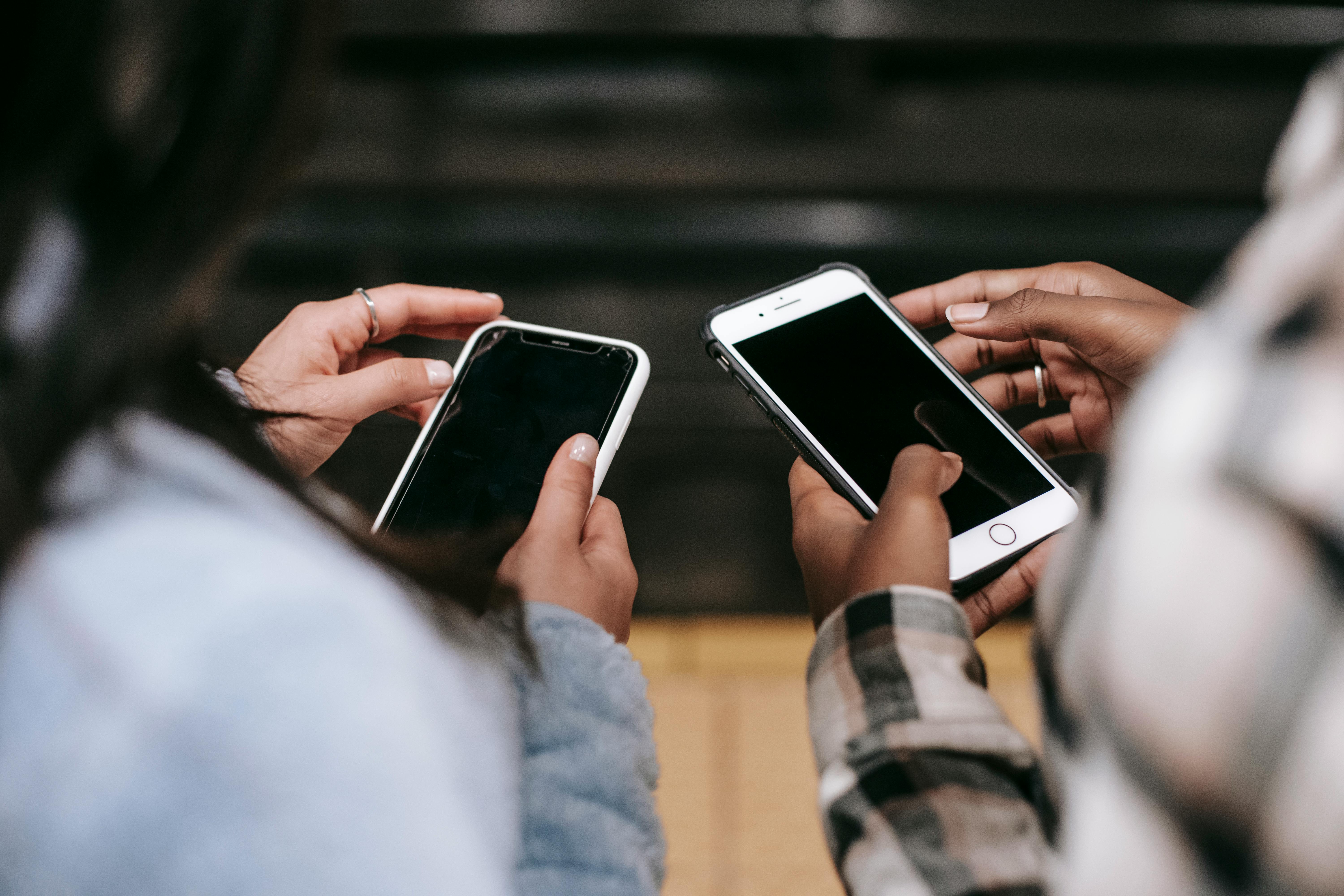 looking down on two people holding mobile phones, side by side