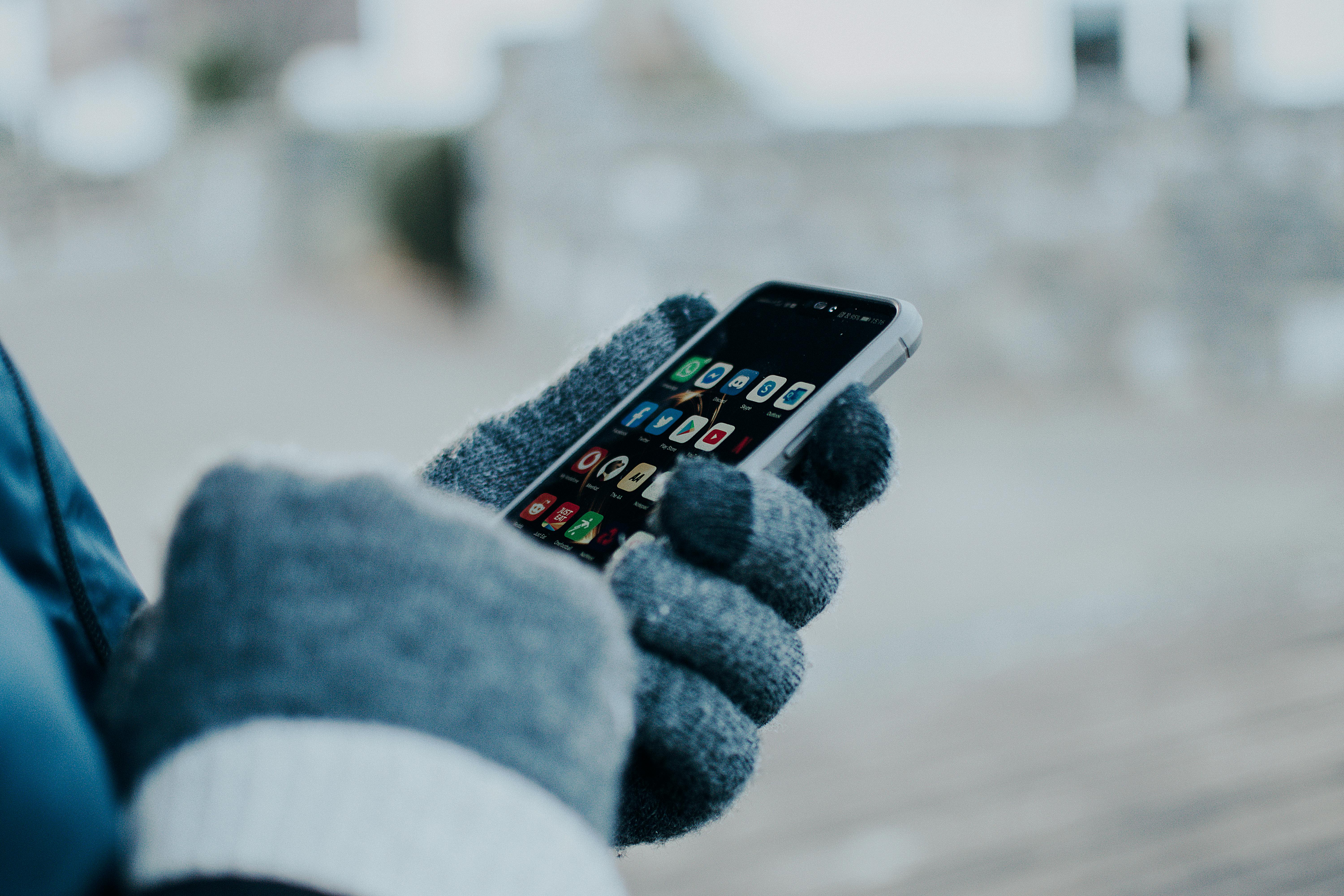 close up of person navigating mobile phone in winter setting